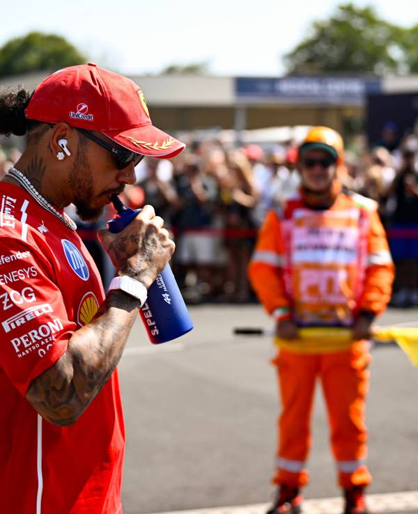 Lewis Hamilton trinkt an einer Flasche.