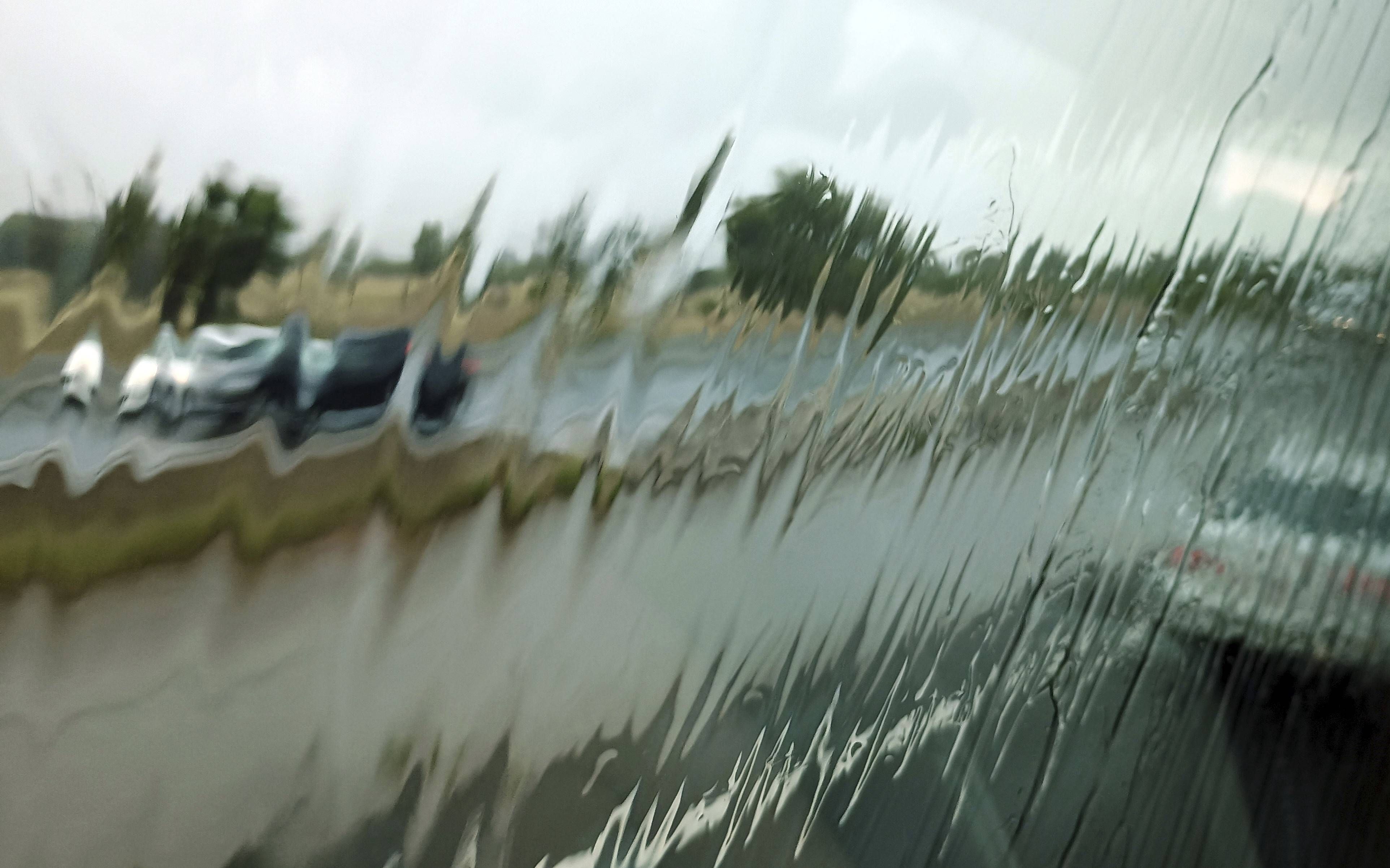 Regen auf Scheibe, verschwommene Fahrzeuge und Straße