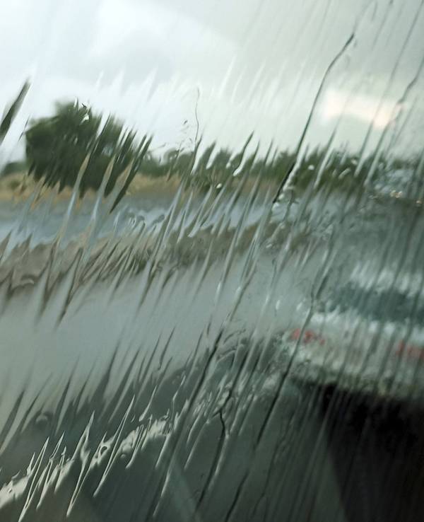 Regen auf Scheibe, verschwommene Fahrzeuge und Straße