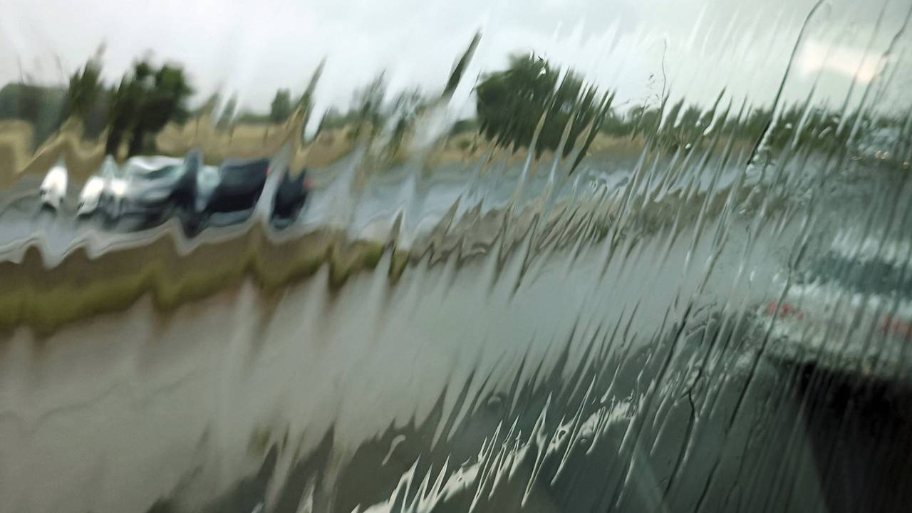 Regen auf Scheibe, verschwommene Fahrzeuge und Straße