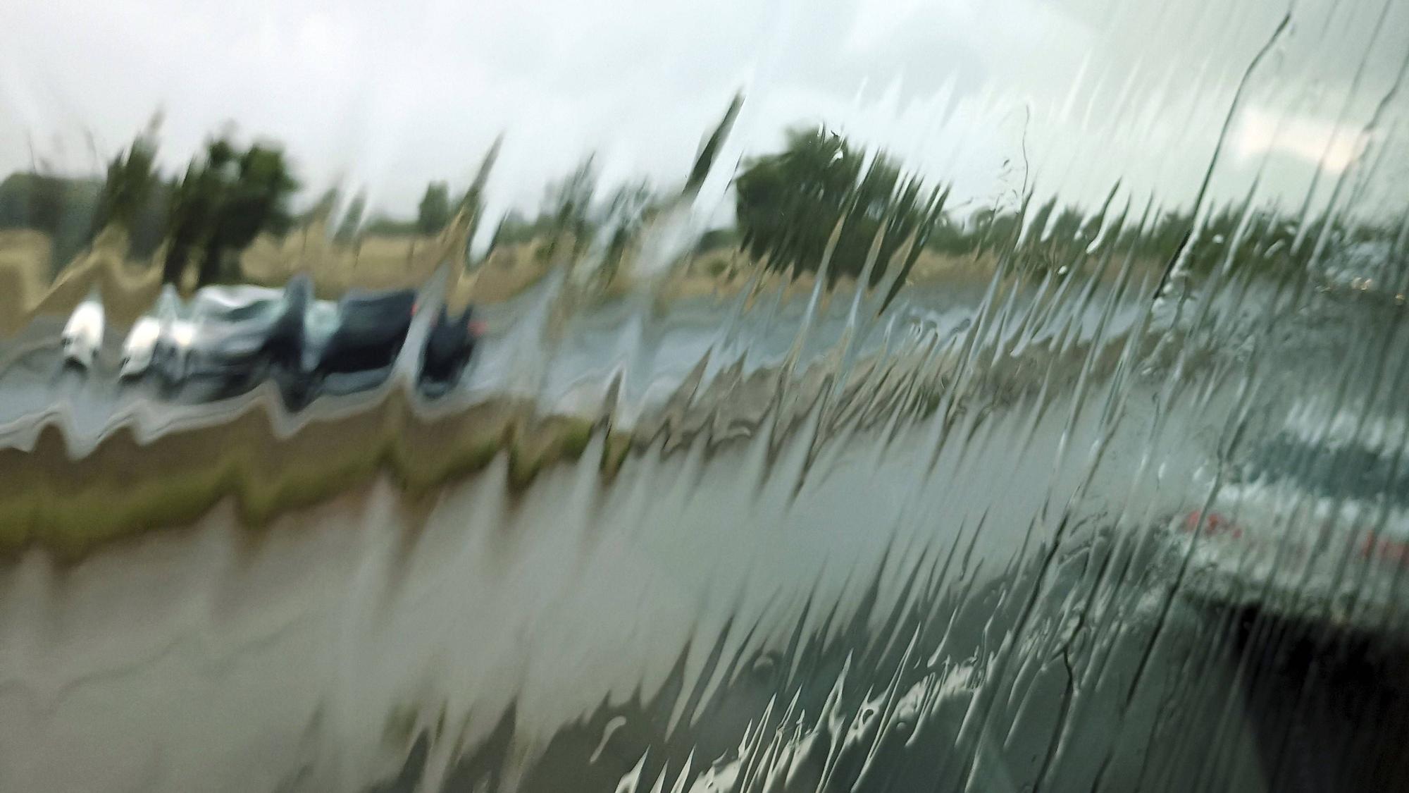 Regen auf Scheibe, verschwommene Fahrzeuge und Straße