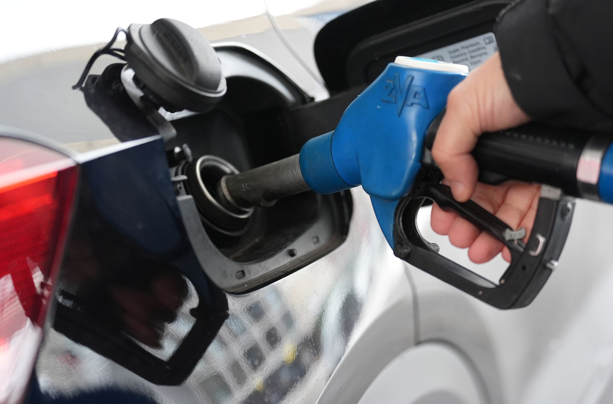 Einer Person steckt einen Zapfstutzen in den Tank eines Autos.