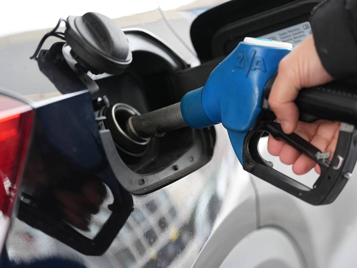 Einer Person steckt einen Zapfstutzen in den Tank eines Autos.