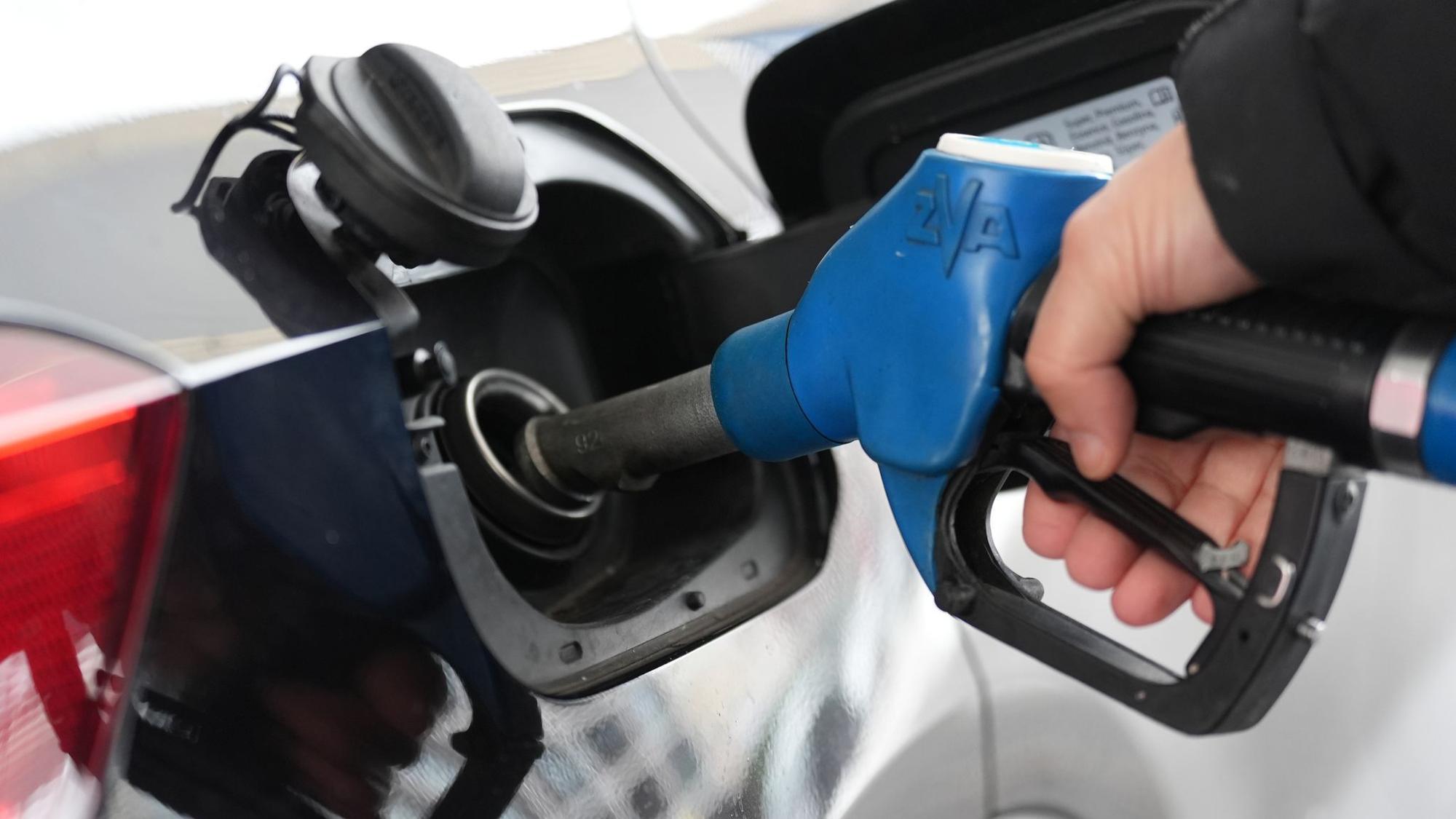 Einer Person steckt einen Zapfstutzen in den Tank eines Autos.