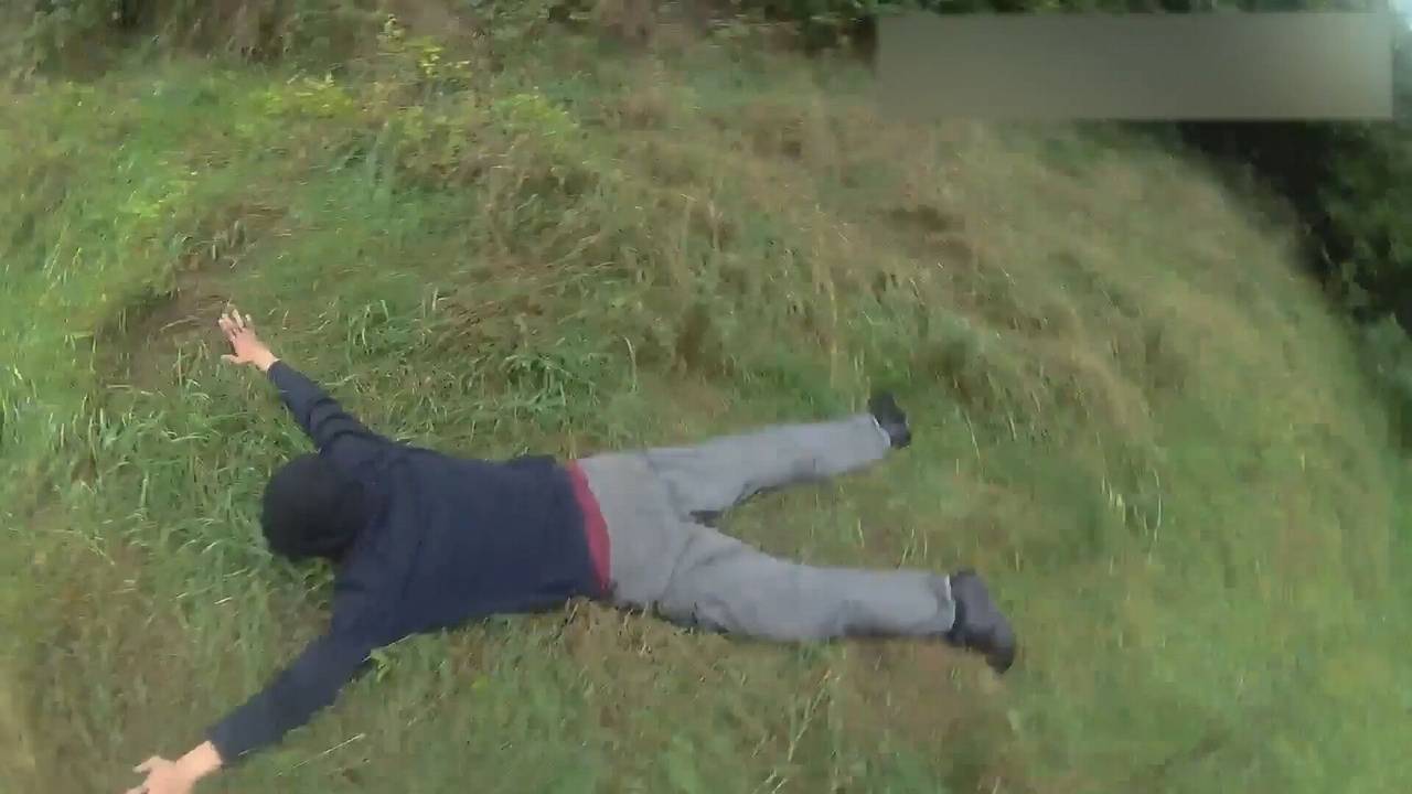 Ein Mann liegt ausgestreckt auf dem Bauch im Gras.