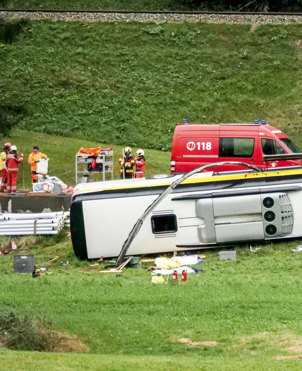Ein Bus liegt neben der Straße auf der Seite, Rettungskräfte wuseln herum.