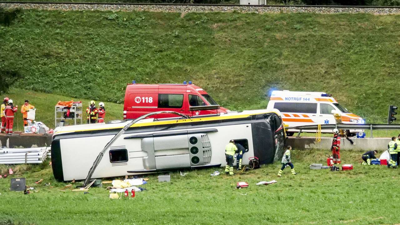 Ein Bus liegt neben der Straße auf der Seite, Rettungskräfte wuseln herum.