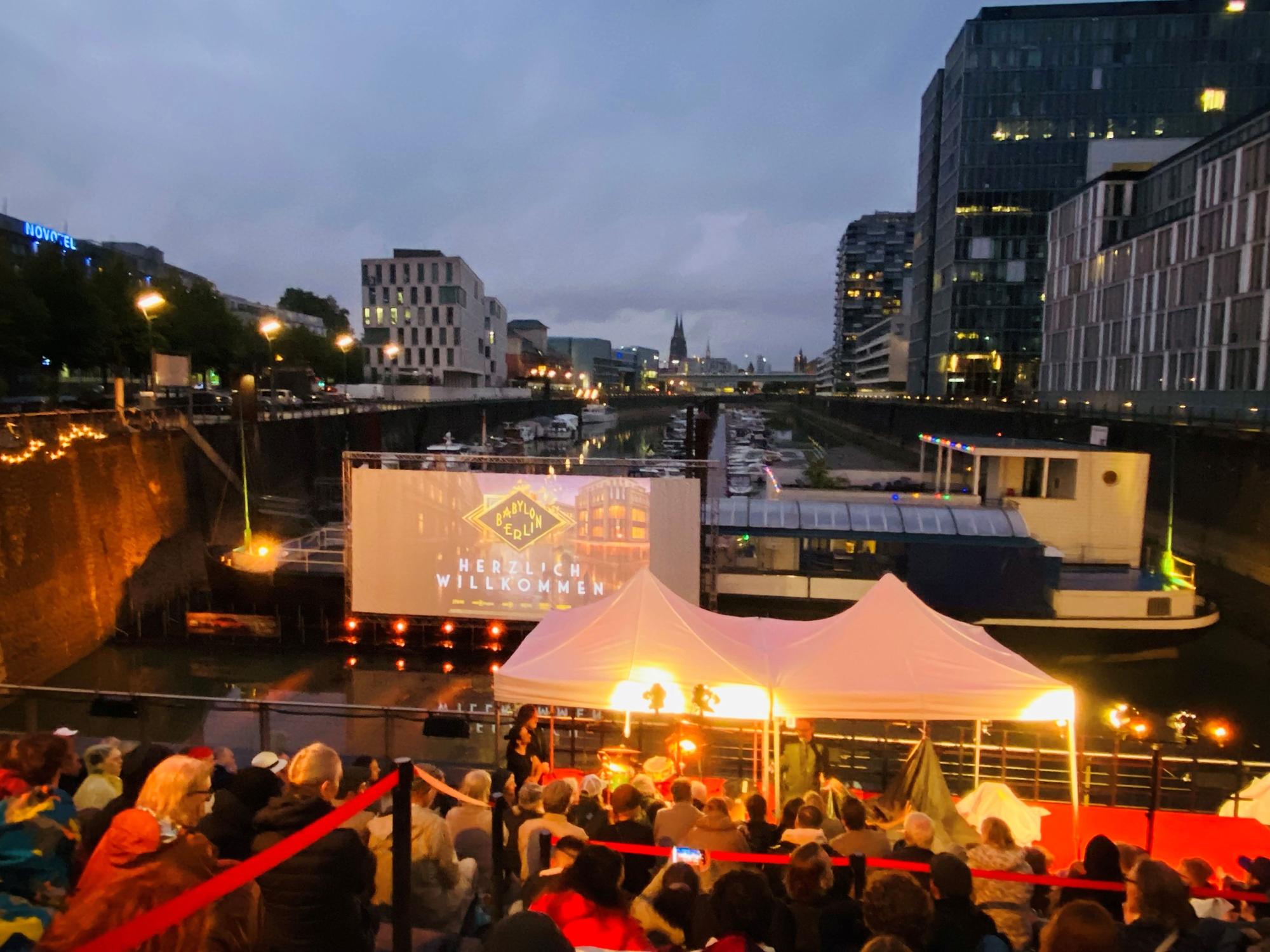 Premieren-Party im Rheinauhafen, Menschen drängen sich vor einer Leinwand.