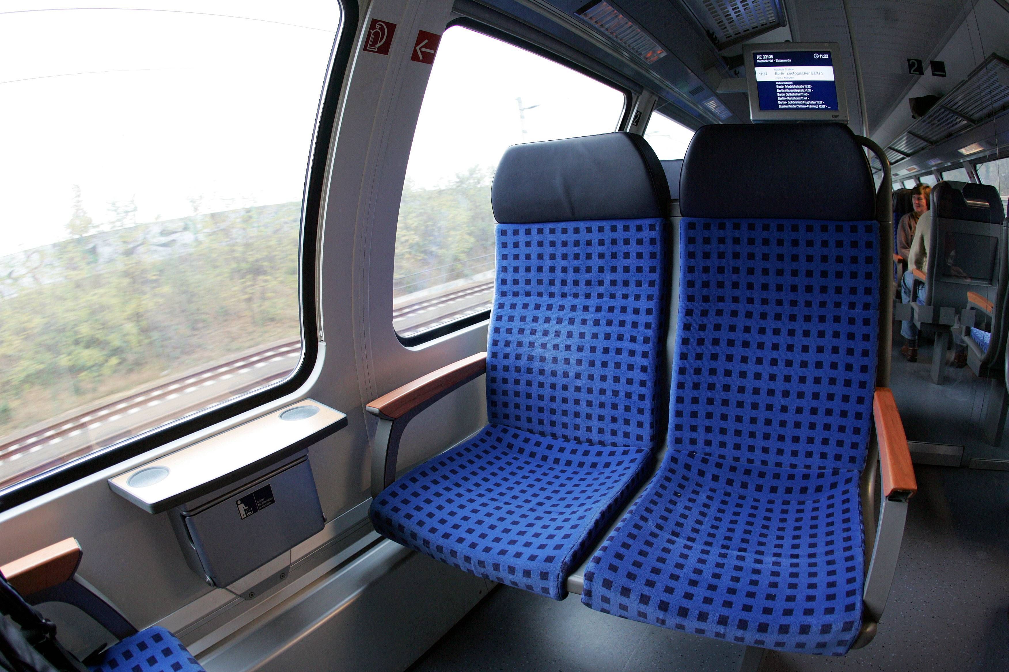 Zugabteil mit Sitzen und einem Fahrgast