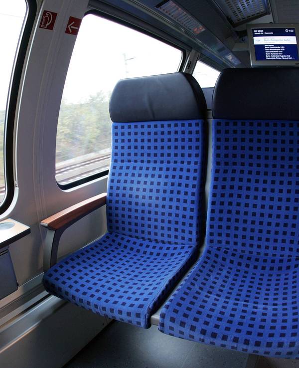 Zugabteil mit Sitzen und einem Fahrgast