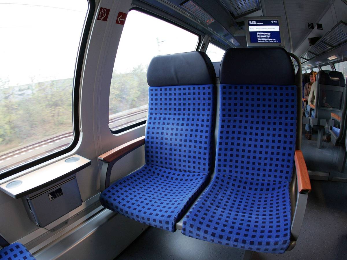 Zugabteil mit Sitzen und einem Fahrgast