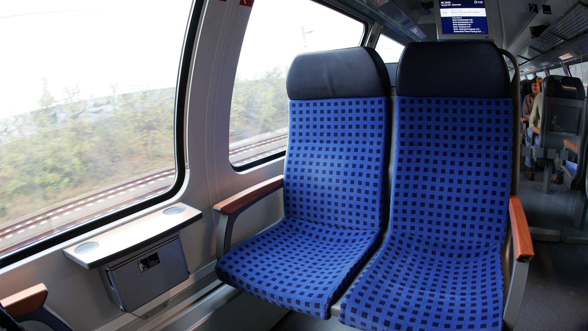 Zugabteil mit Sitzen und einem Fahrgast