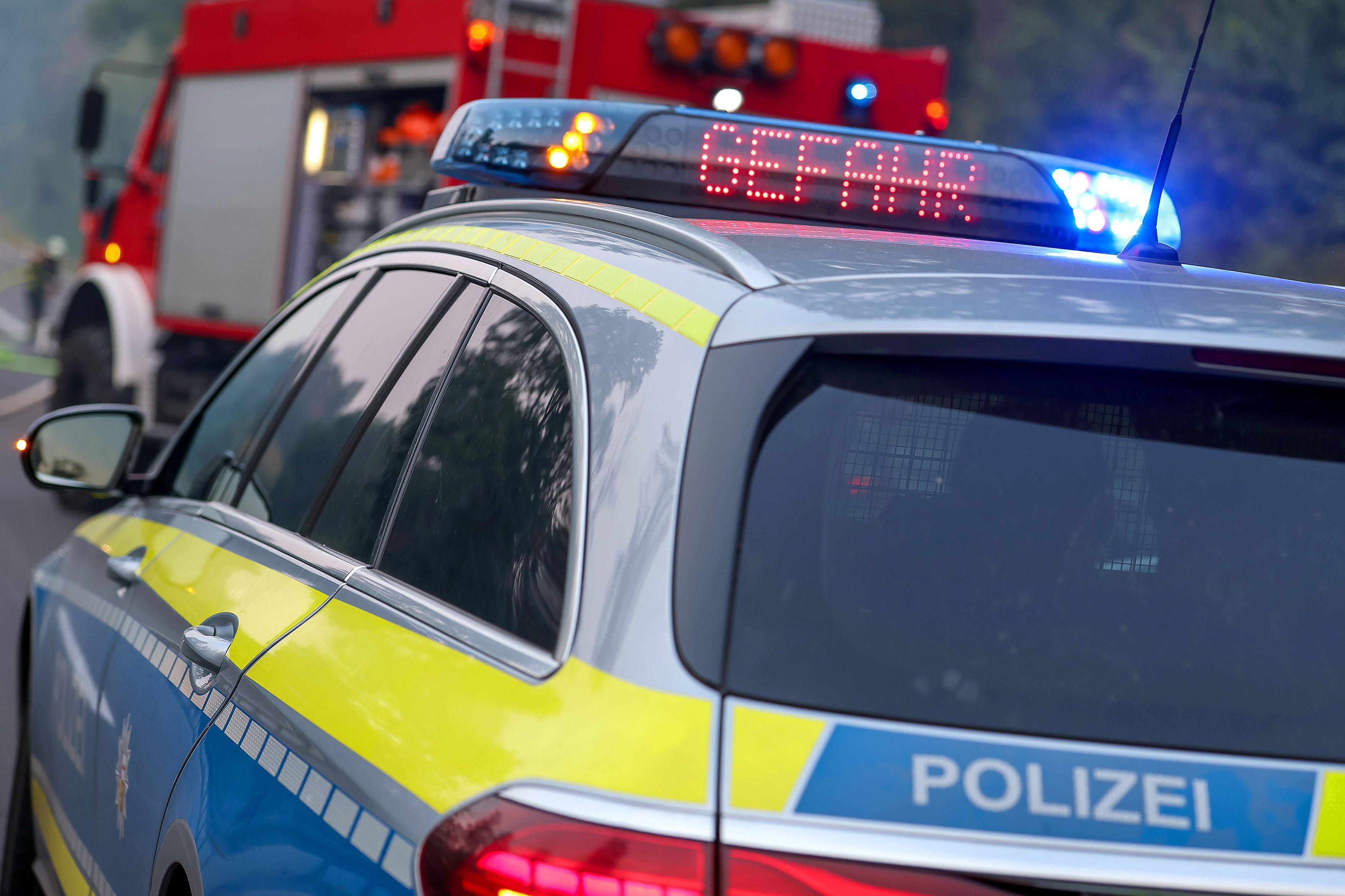 Polizeiauto und Feuerwehrauto mit Blaulicht, Aufschrift Gefahr