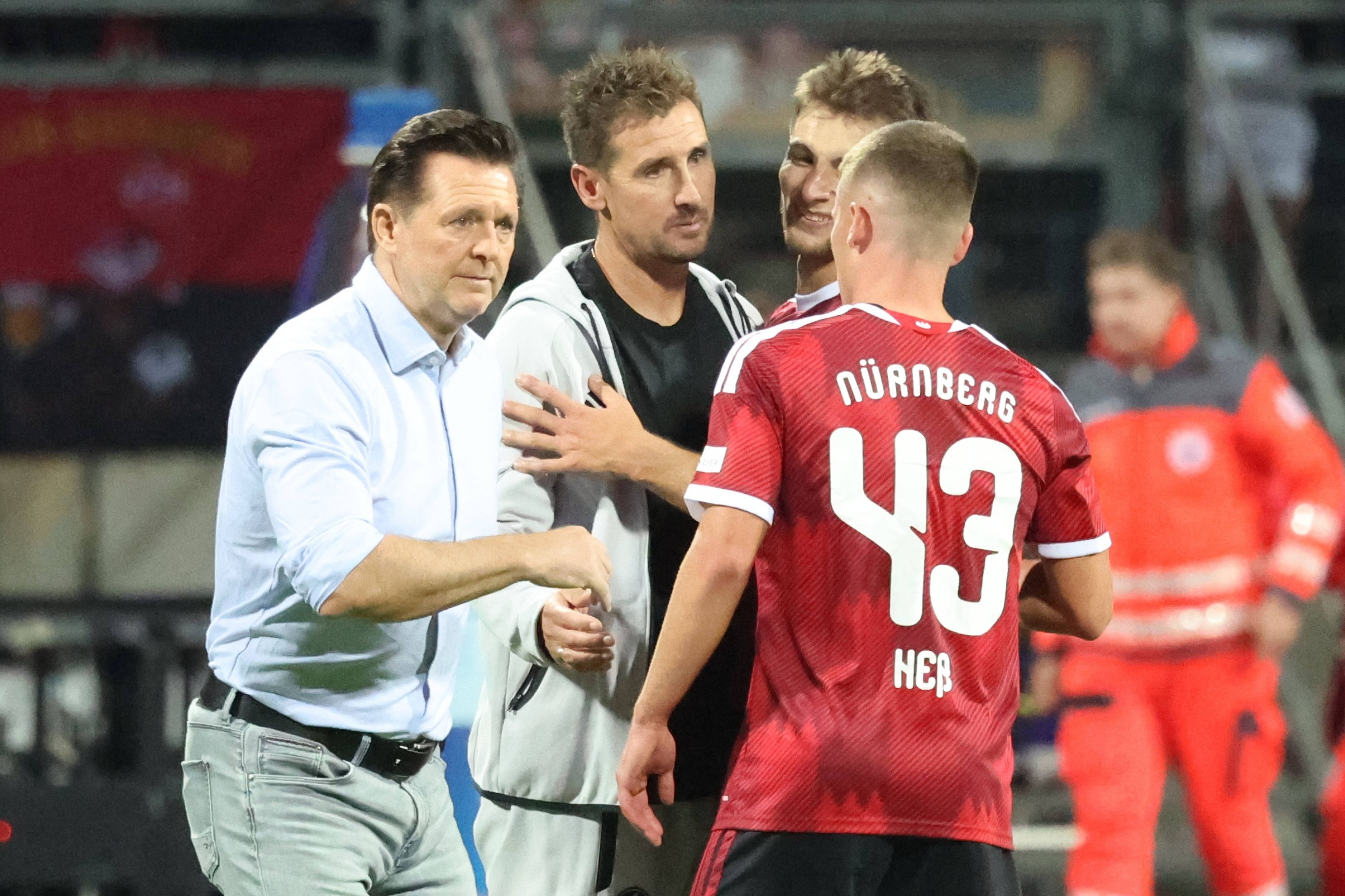 Christian Titz und Miroslav Klose klatschen einen Spieler ab.