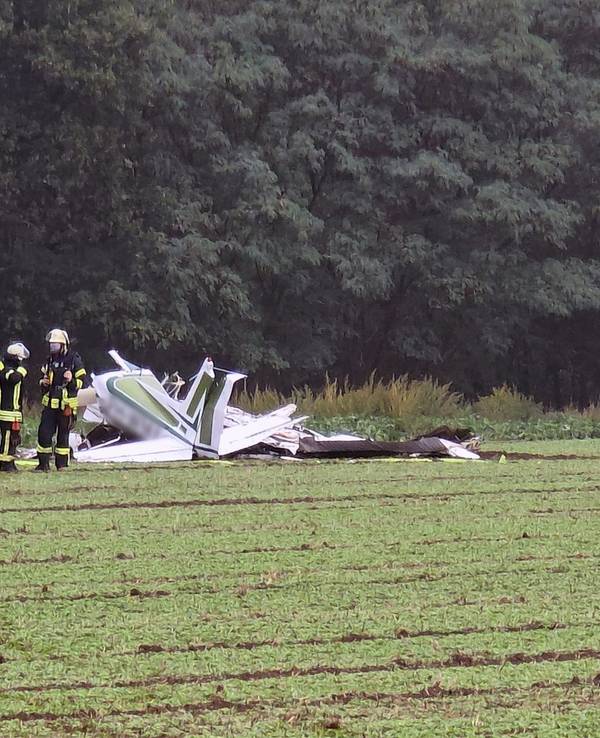 Ein zerschelltes Kleinflugzeug liegt auf einem Acker, Feuerwehrleute sind im Einsatz.