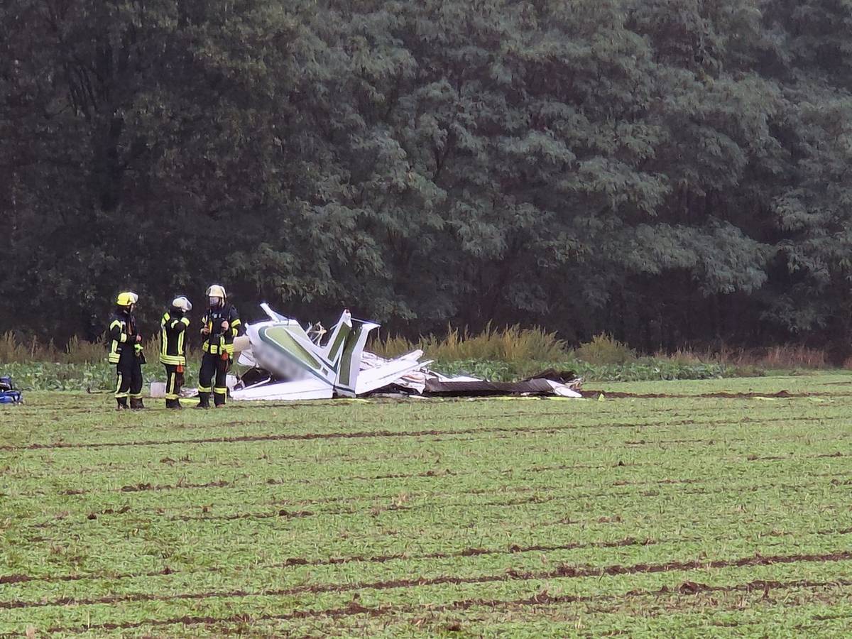 Ein zerschelltes Kleinflugzeug liegt auf einem Acker, Feuerwehrleute sind im Einsatz.