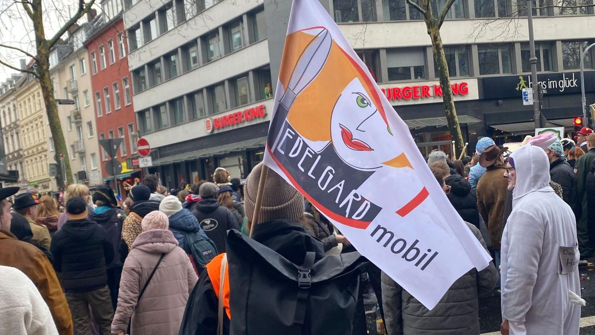 Eine Frau steht mit einer Edelgard-Flagge in einer Menge.