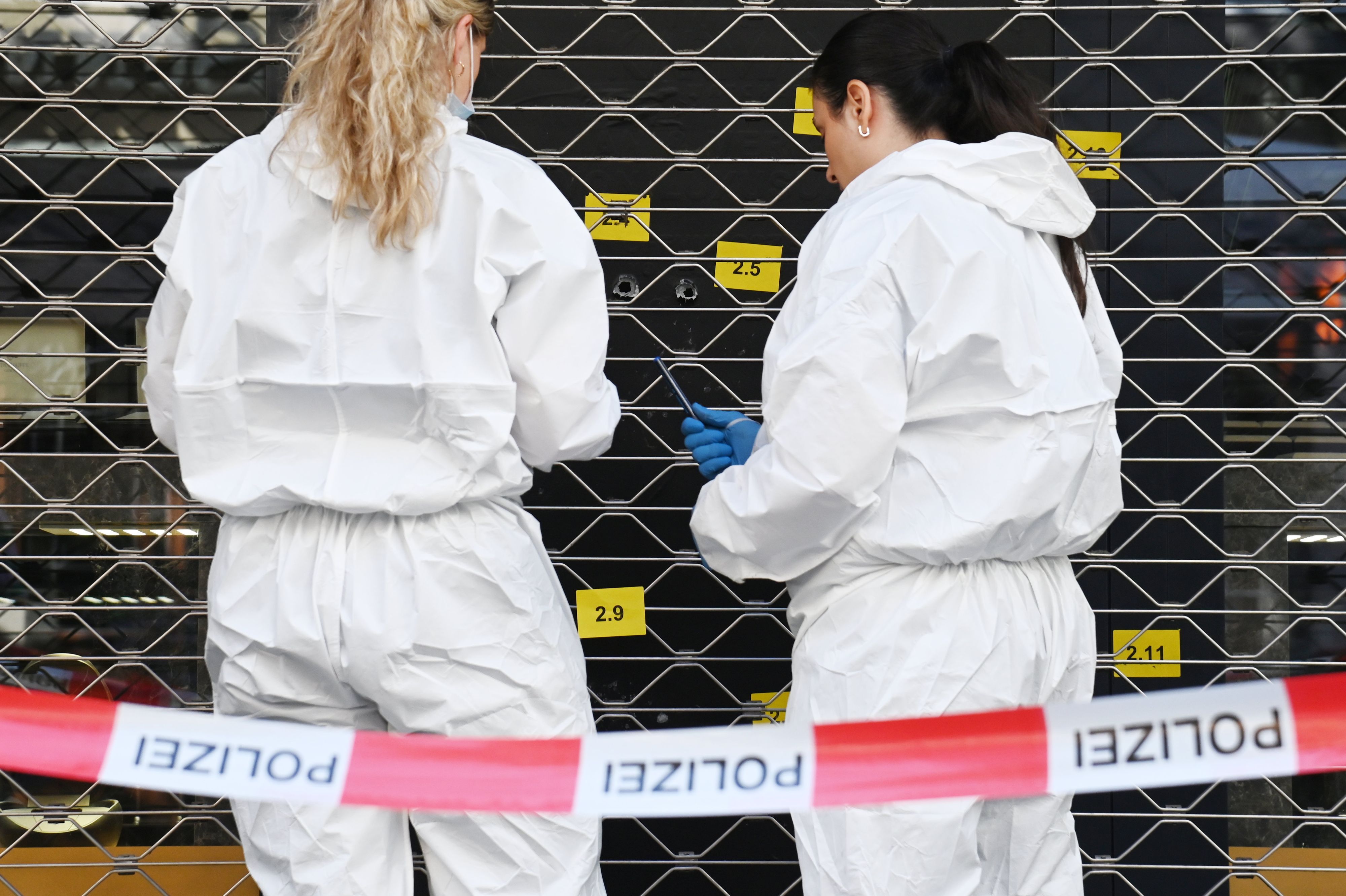 Zwei Beamtinnen sichern an einer Scheibe, in der mehrere Einschlusslöcher klaffen, Spuren.