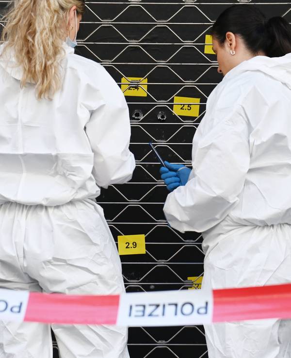 Zwei Beamtinnen sichern an einer Scheibe, in der mehrere Einschlusslöcher klaffen, Spuren.