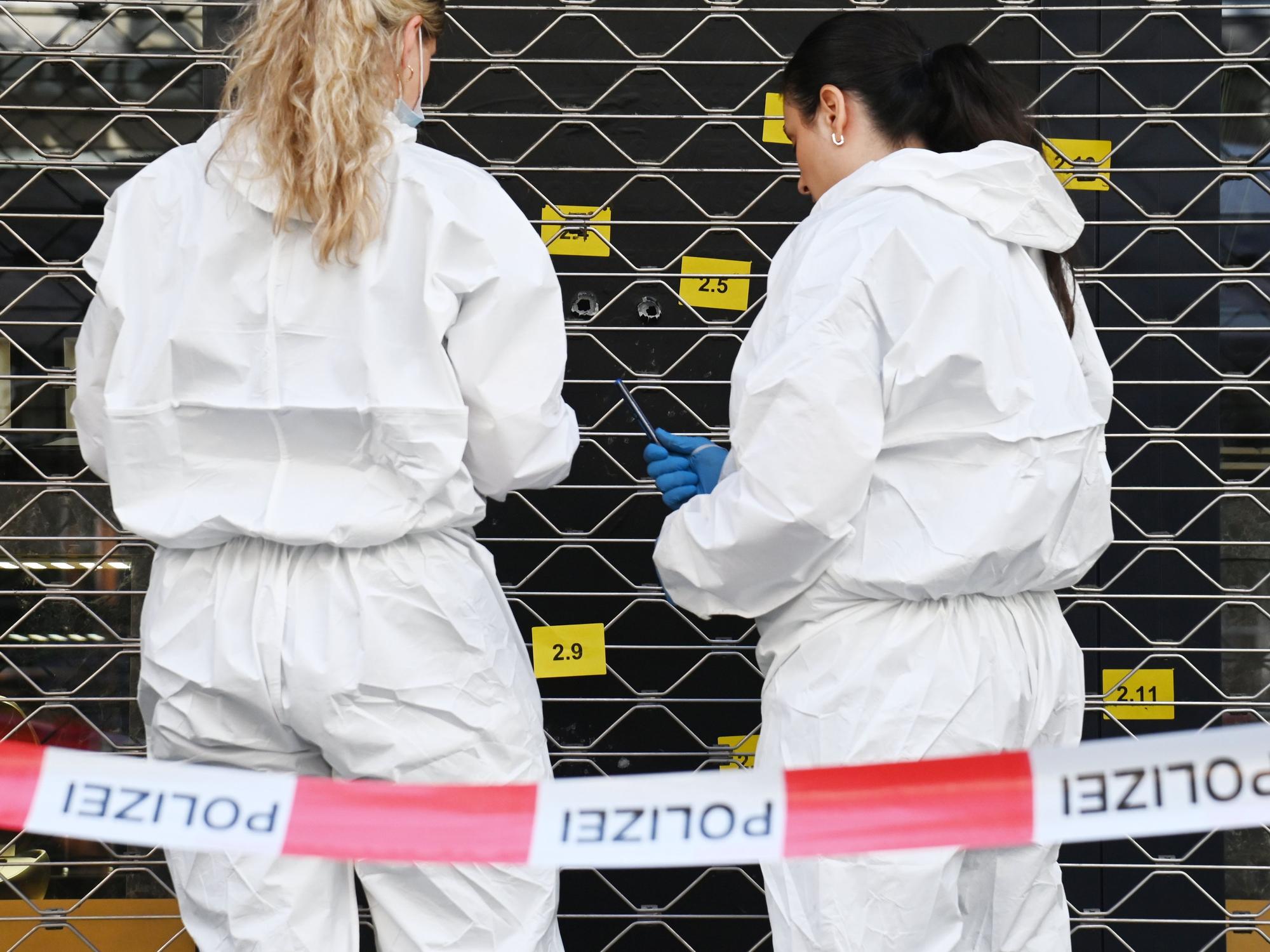 Zwei Beamtinnen sichern an einer Scheibe, in der mehrere Einschlusslöcher klaffen, Spuren.