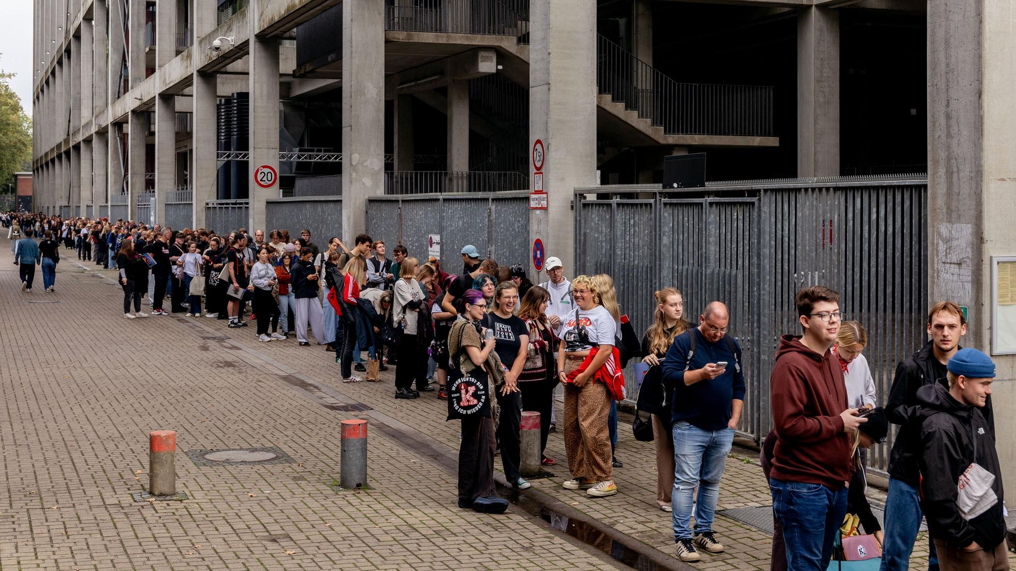 Fans warten in einer Schlange vor dem Kölner Stadion.