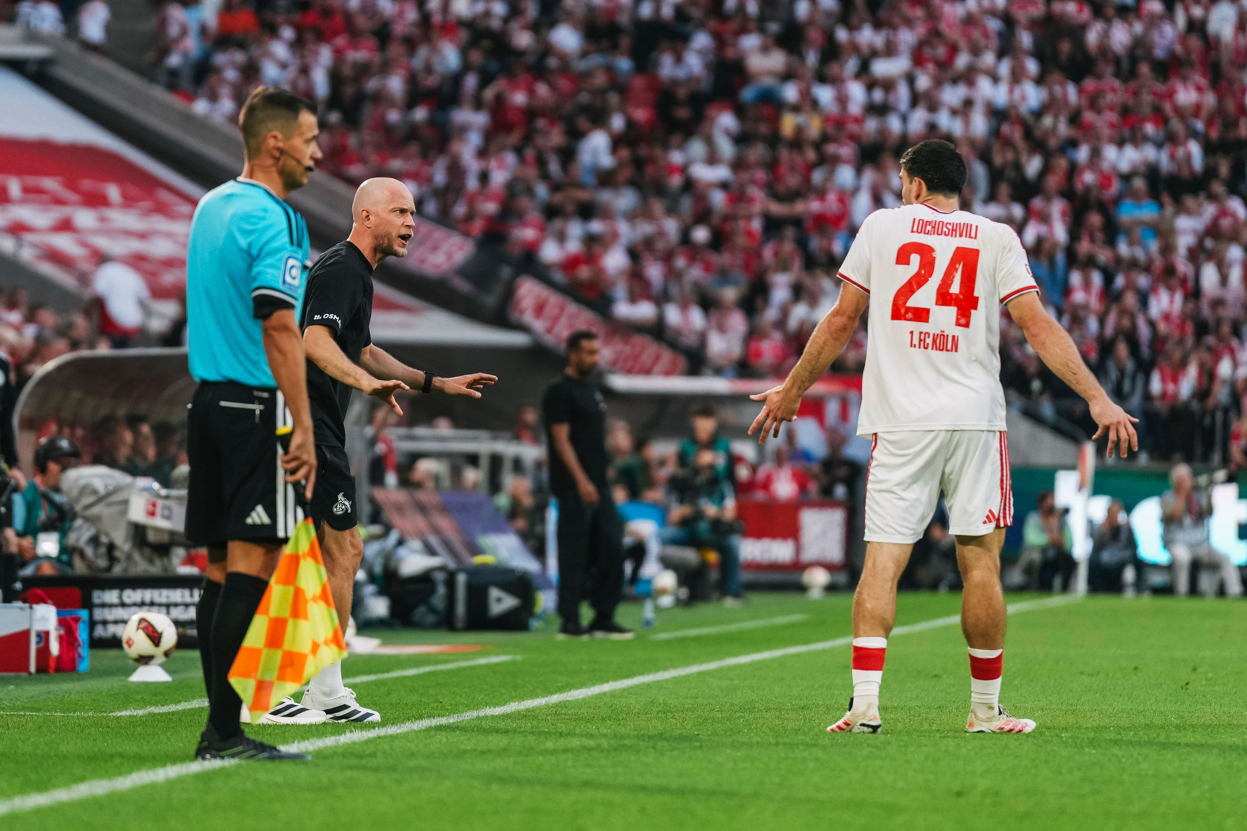 René Wagner (1. FC Köln) spricht mit Verteidiger Luka Lochoshvili, der mit den Schultern zuckt.