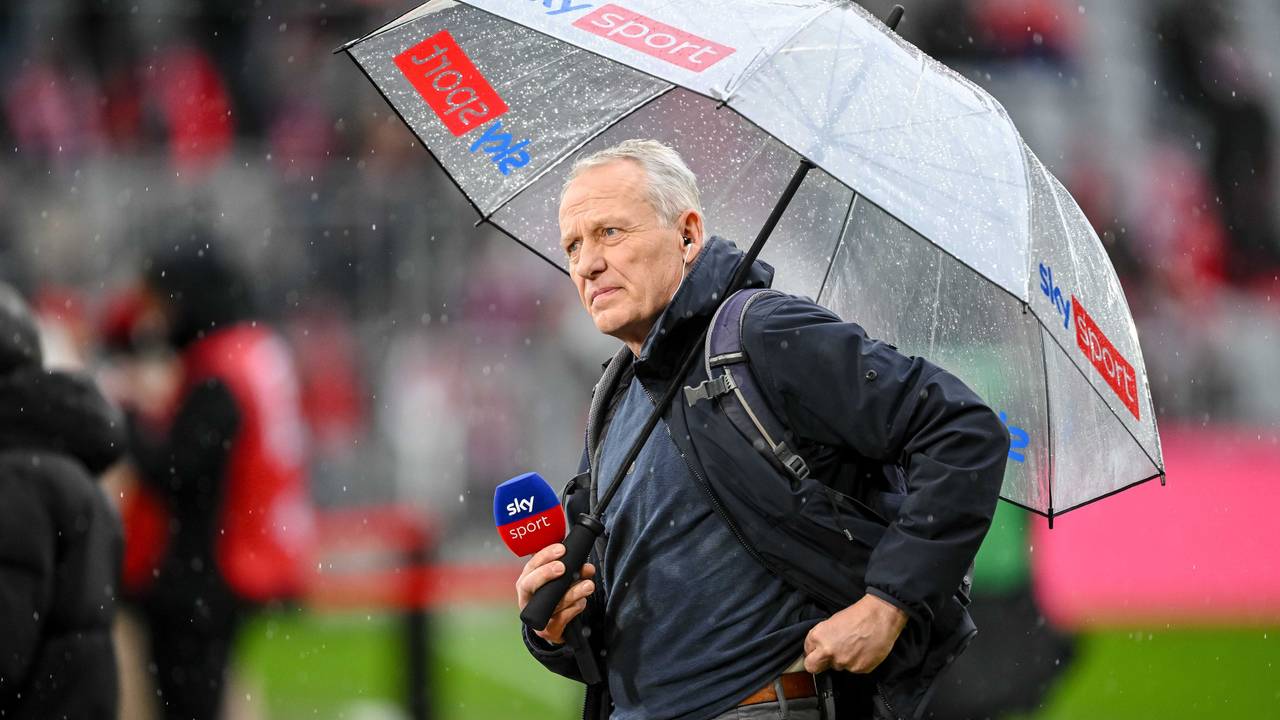 Christian Streich mit Mikrofon und Regenschirm