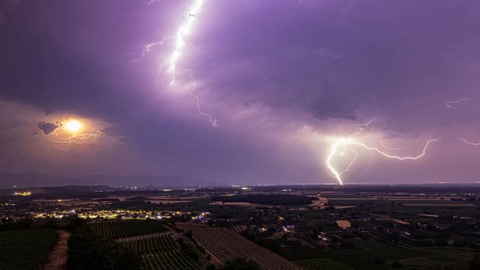 Ein Blitz geht über dem Rheintal nieder während im Vordergrund der Kaiserstuhl zu sehen ist.