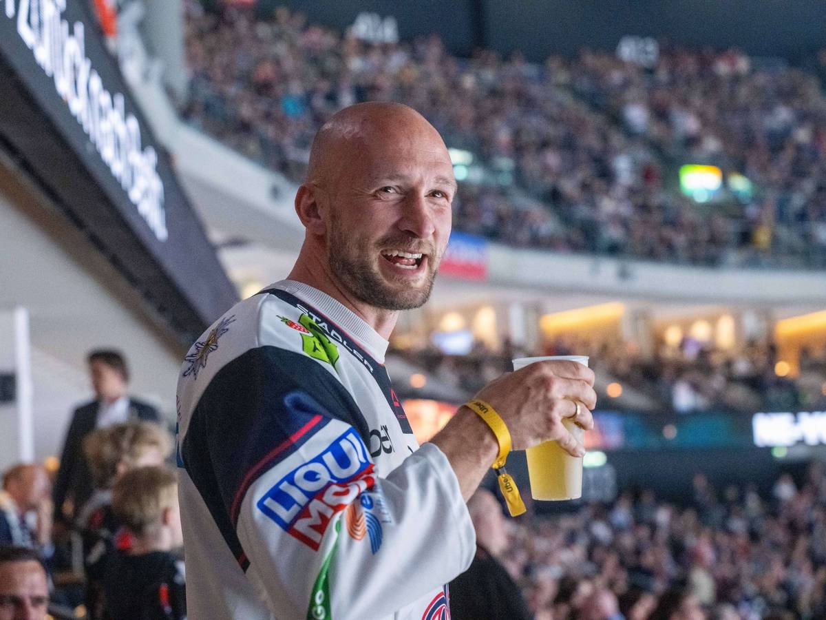 Toni Leistner mit Bierbecher in der Hand auf der Tribüne.