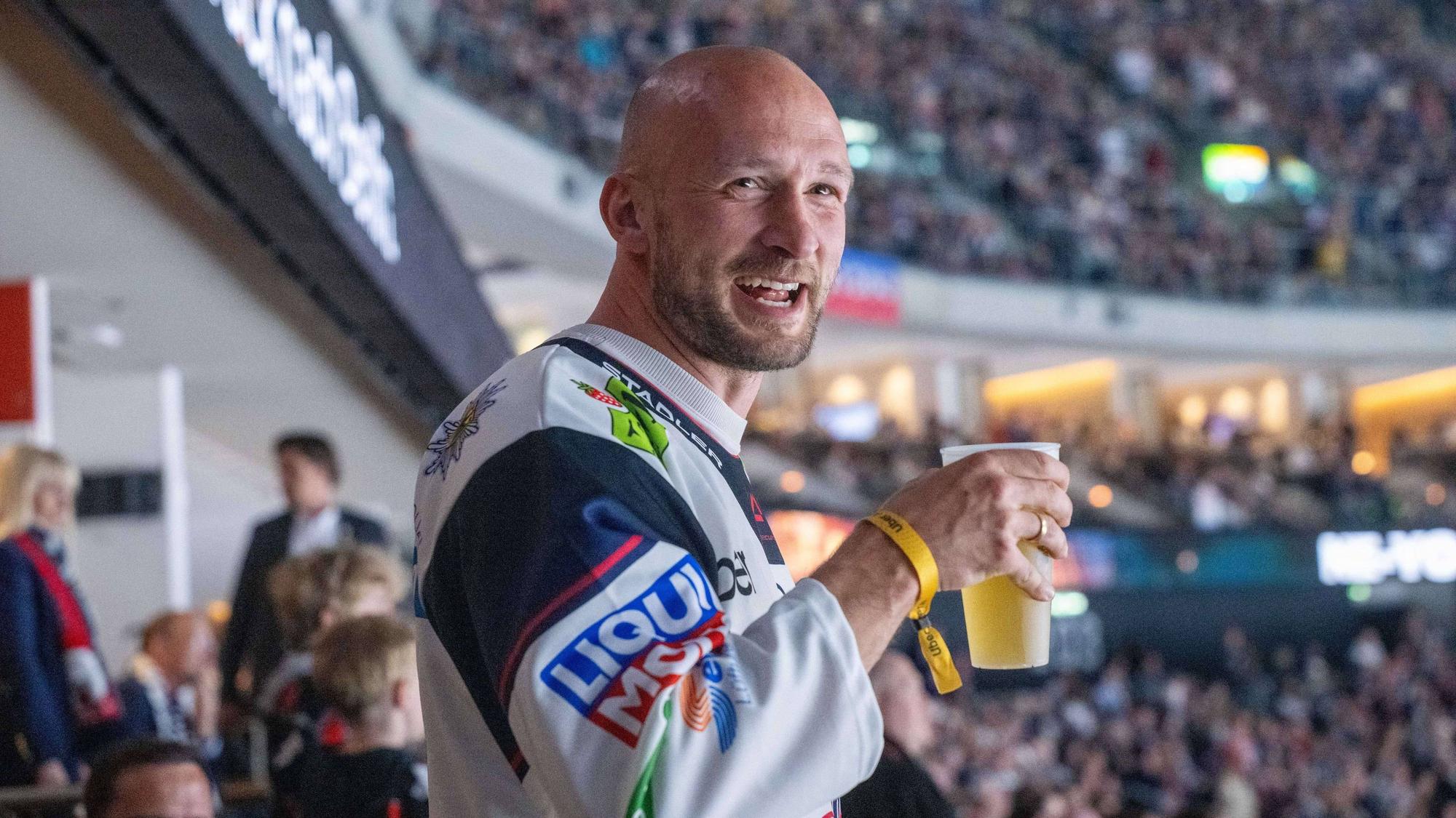 Toni Leistner mit Bierbecher in der Hand auf der Tribüne.