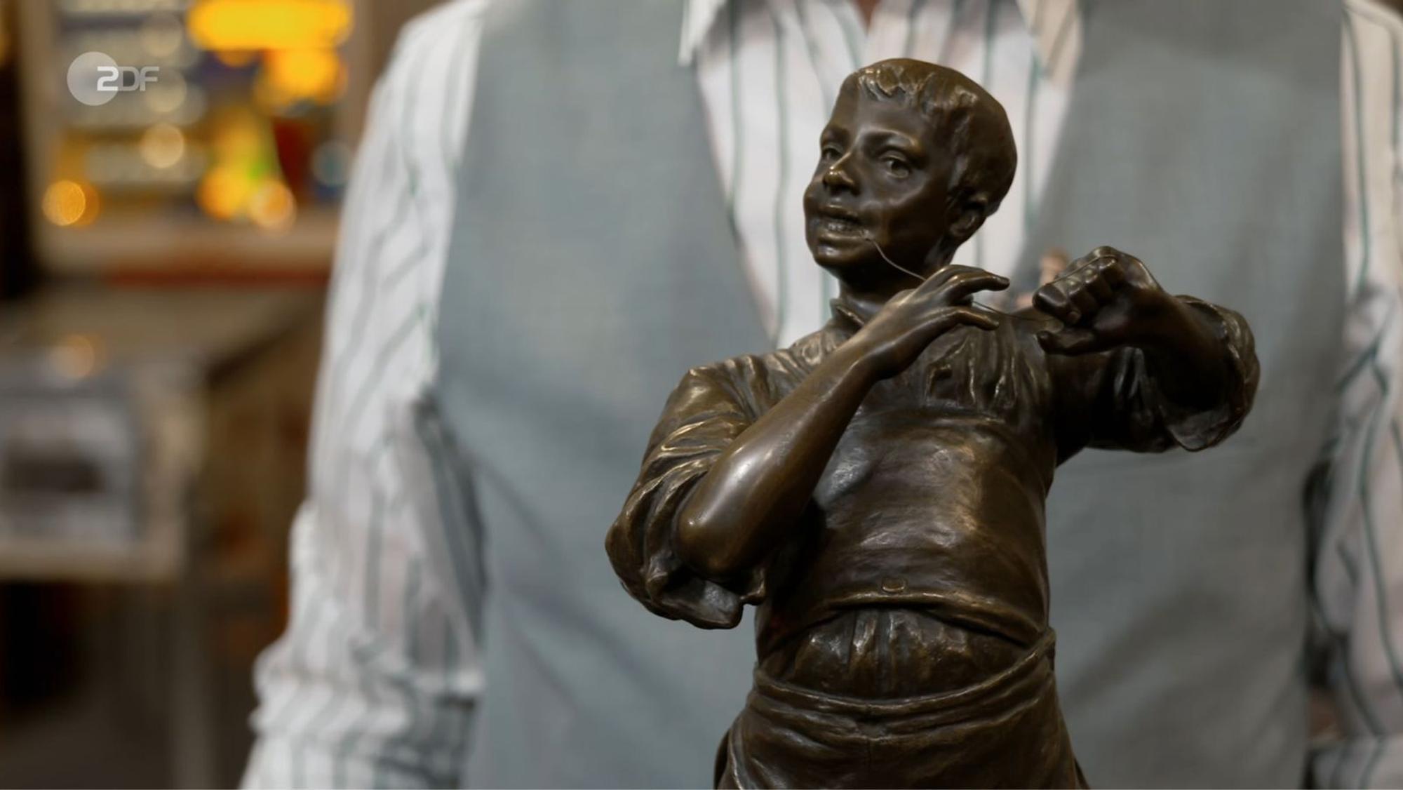 „Der will sich einen Zahn ziehen“, vermutete Lichter. Die Händler fragten sich, ob der Junge angelte, Flöte spielte oder Zahnseide benutzte. Silvio erklärte: Die Bronze-Statuette hieß „Der Saitenspieler“. Friedrich Häusser bezahlte 2.100 Euro - 100 über der Expertise. (Bild: ZDF)