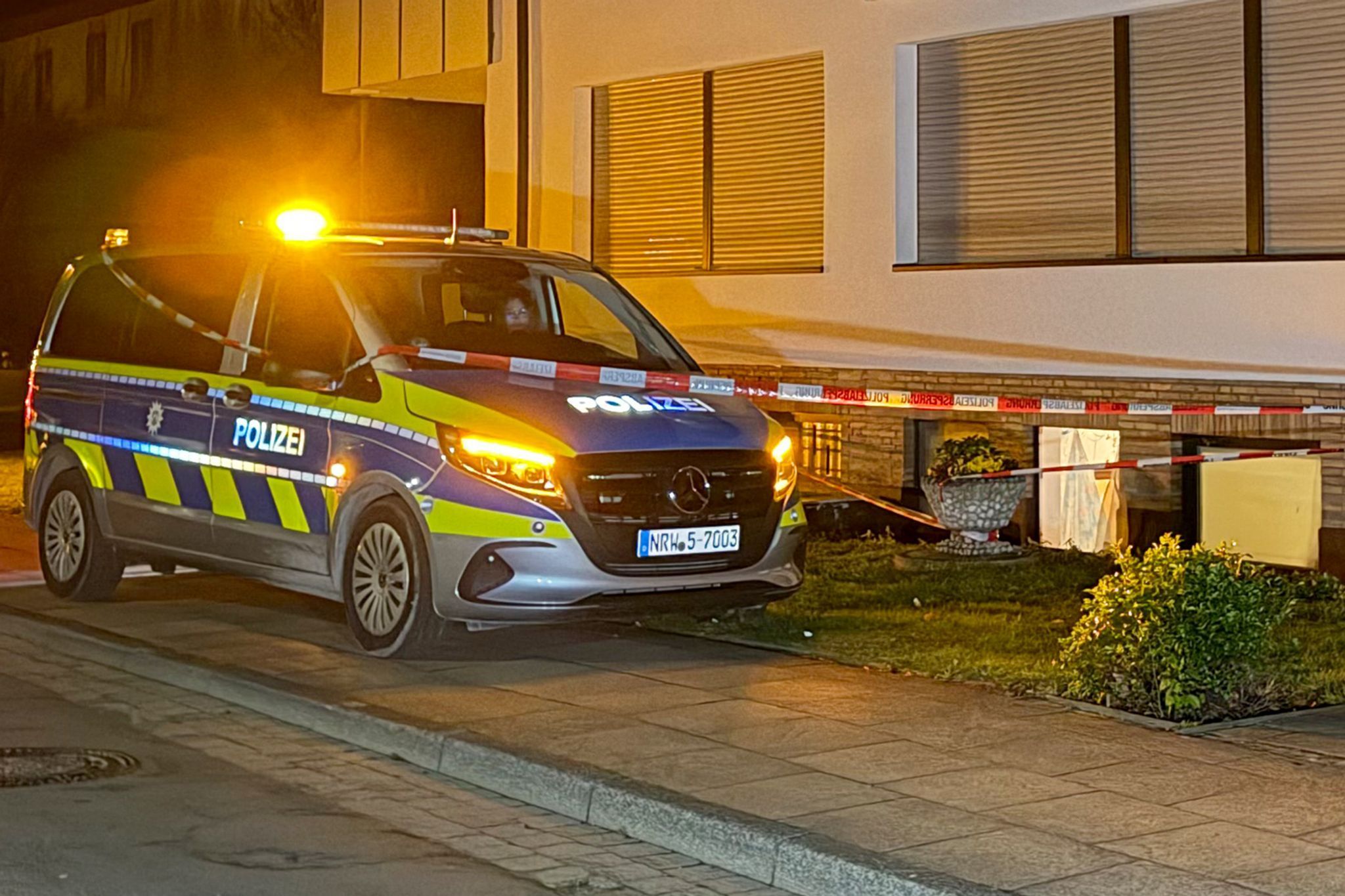 Ein Polizeifahrzeug steht vor einem Haus.