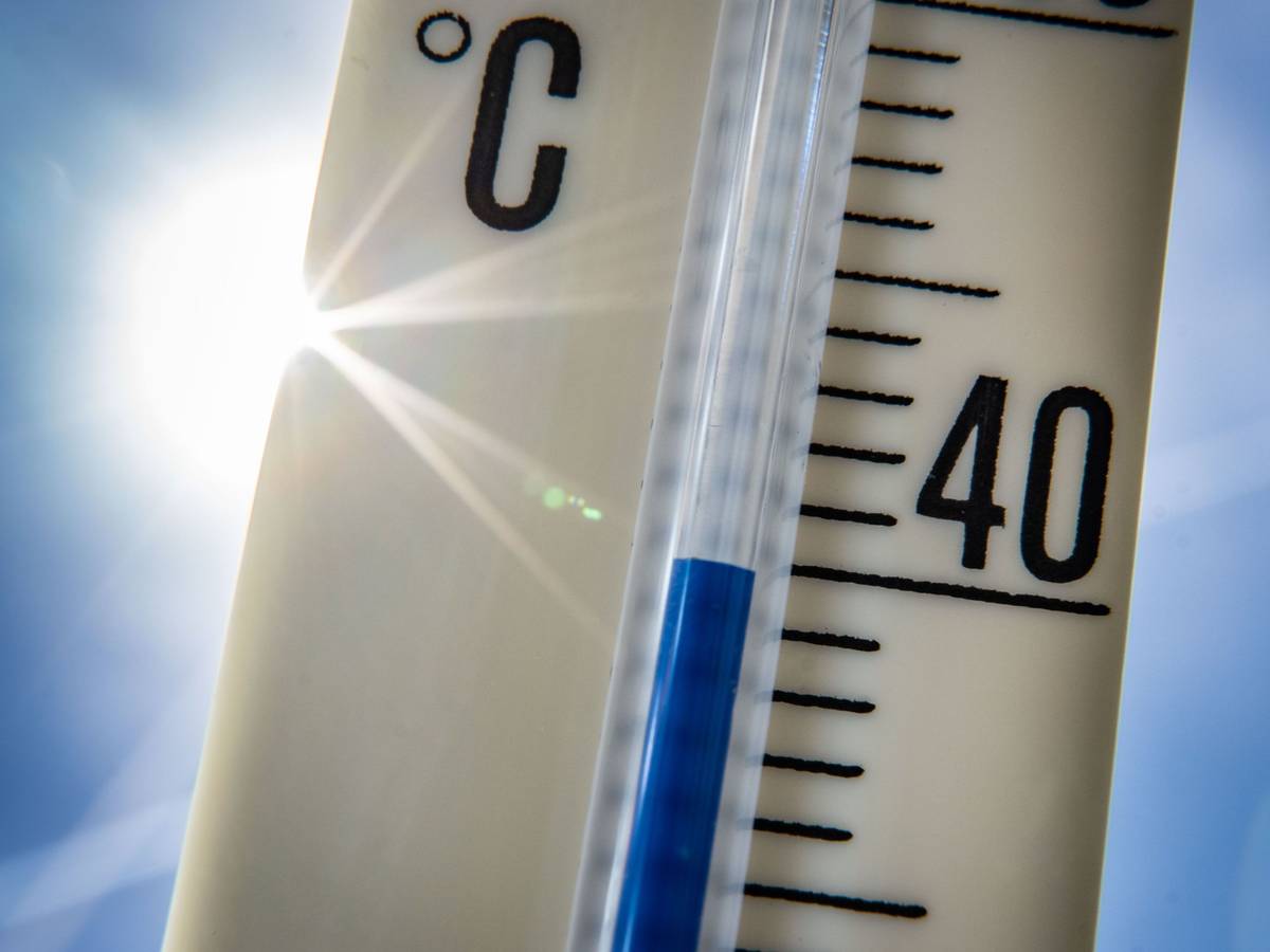 Ein Außenthermometer zeigt vor dem blauen Himmel und der Sonne eine Temperatur von nahezu 40 Grad Celsius an.