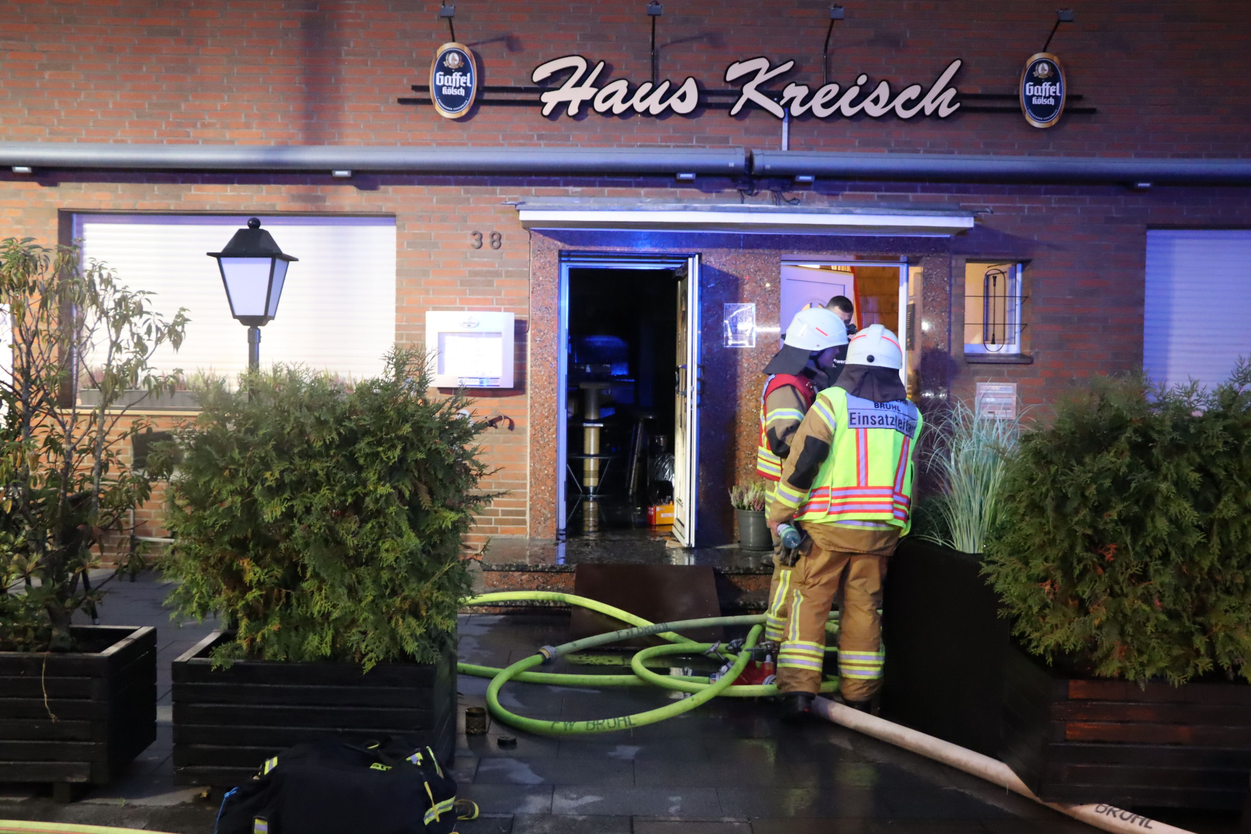 Zu sehen sind Feuerwehrleute vor dem Gebäude der Gaststätte.