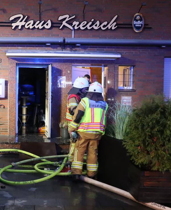 Zu sehen sind Feuerwehrleute vor dem Gebäude der Gaststätte.