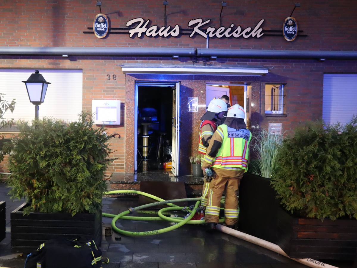 Zu sehen sind Feuerwehrleute vor dem Gebäude der Gaststätte.