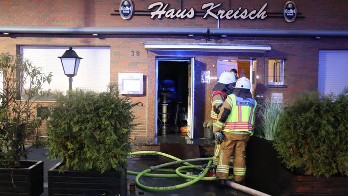Zu sehen sind Feuerwehrleute vor dem Gebäude der Gaststätte.