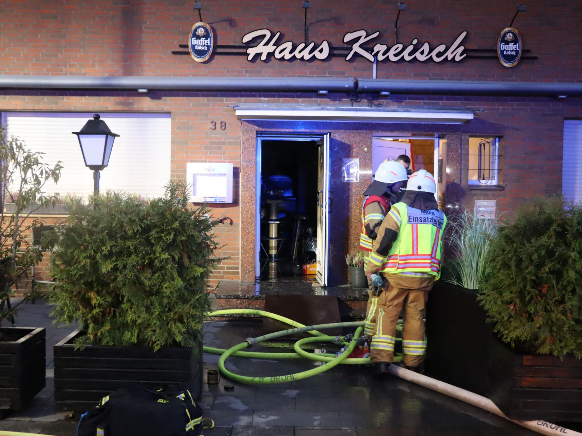 Zu sehen sind Feuerwehrleute vor dem Gebäude der Gaststätte.