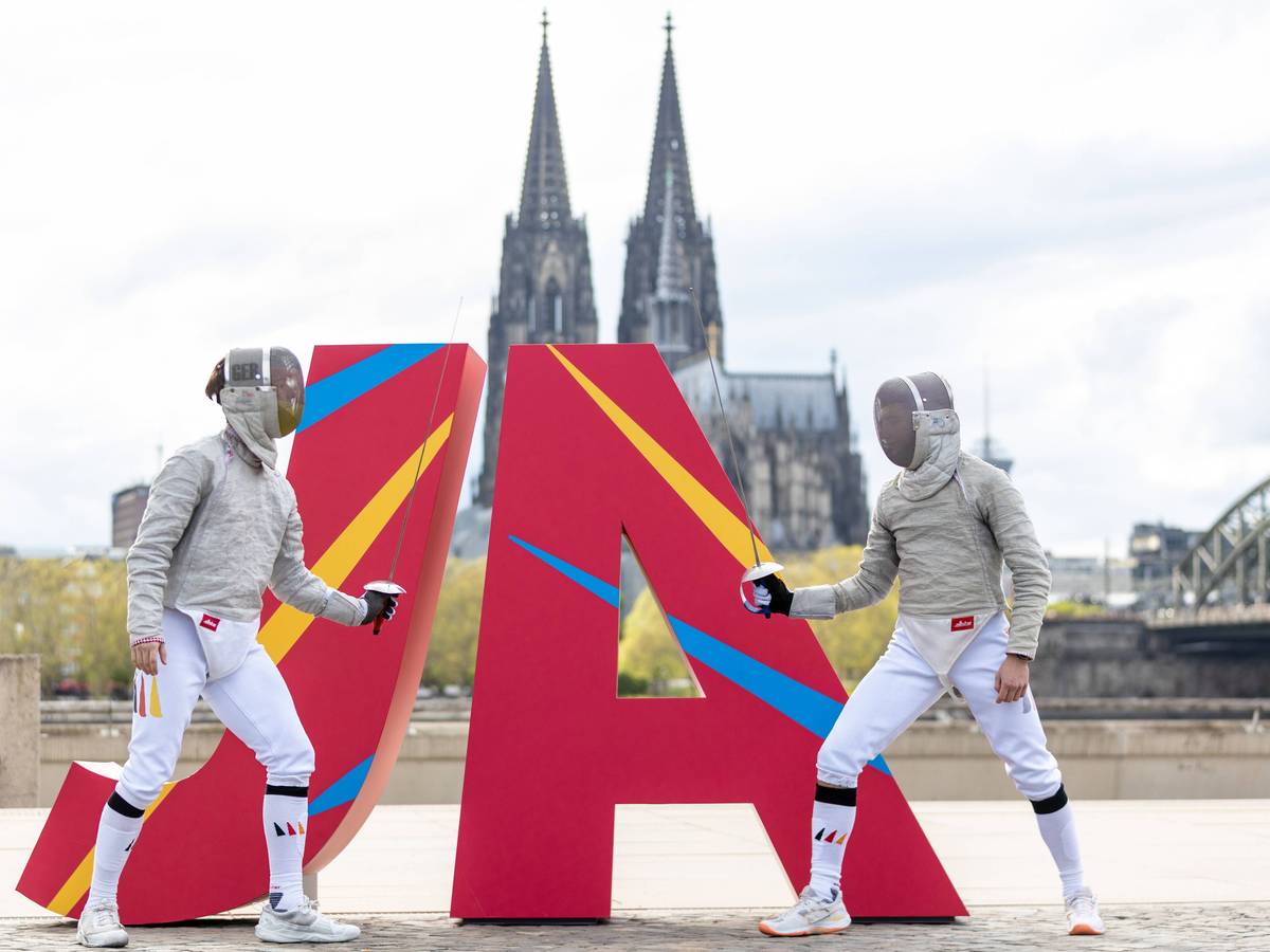 Zwei Fechter vor eine JA Logo vor dem Kölner Dom.