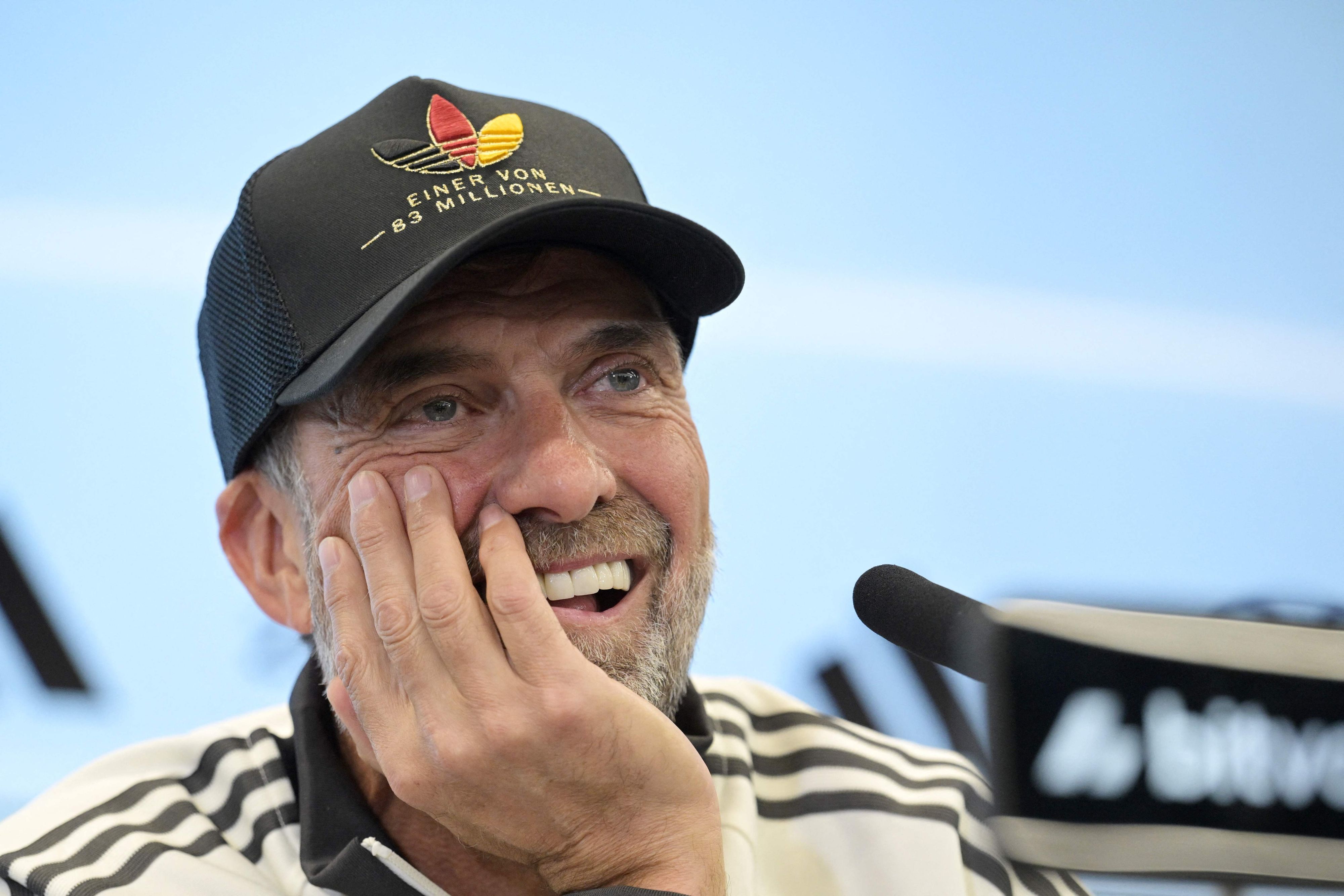 Jürgen Klopp hat den Kopf auf eine Hand abgestützt und lächelt.
