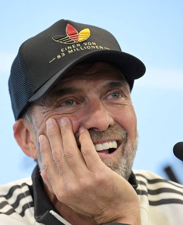 Jürgen Klopp hat den Kopf auf eine Hand abgestützt und lächelt.