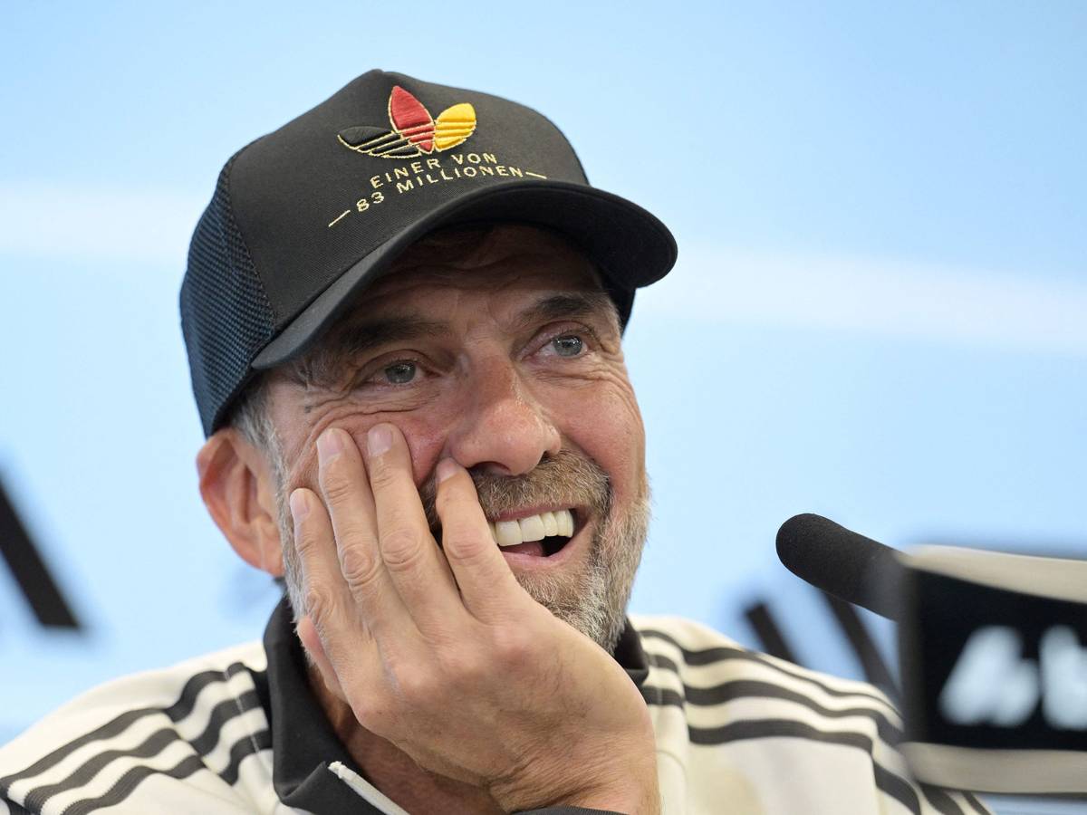 Jürgen Klopp hat den Kopf auf eine Hand abgestützt und lächelt.