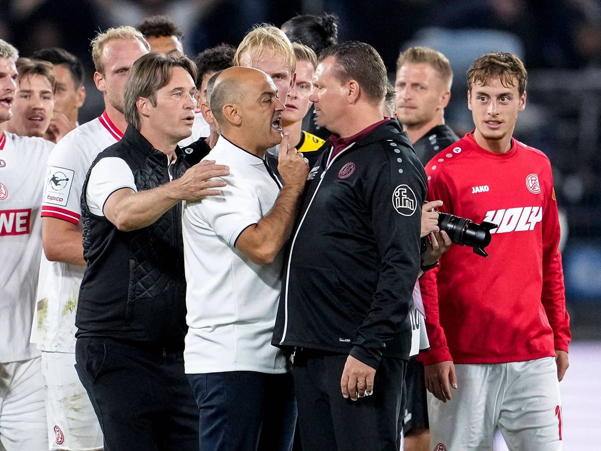 Gerhard Zuber hält Rui Mota zurück, der auf Uwe Koschinat einspricht.