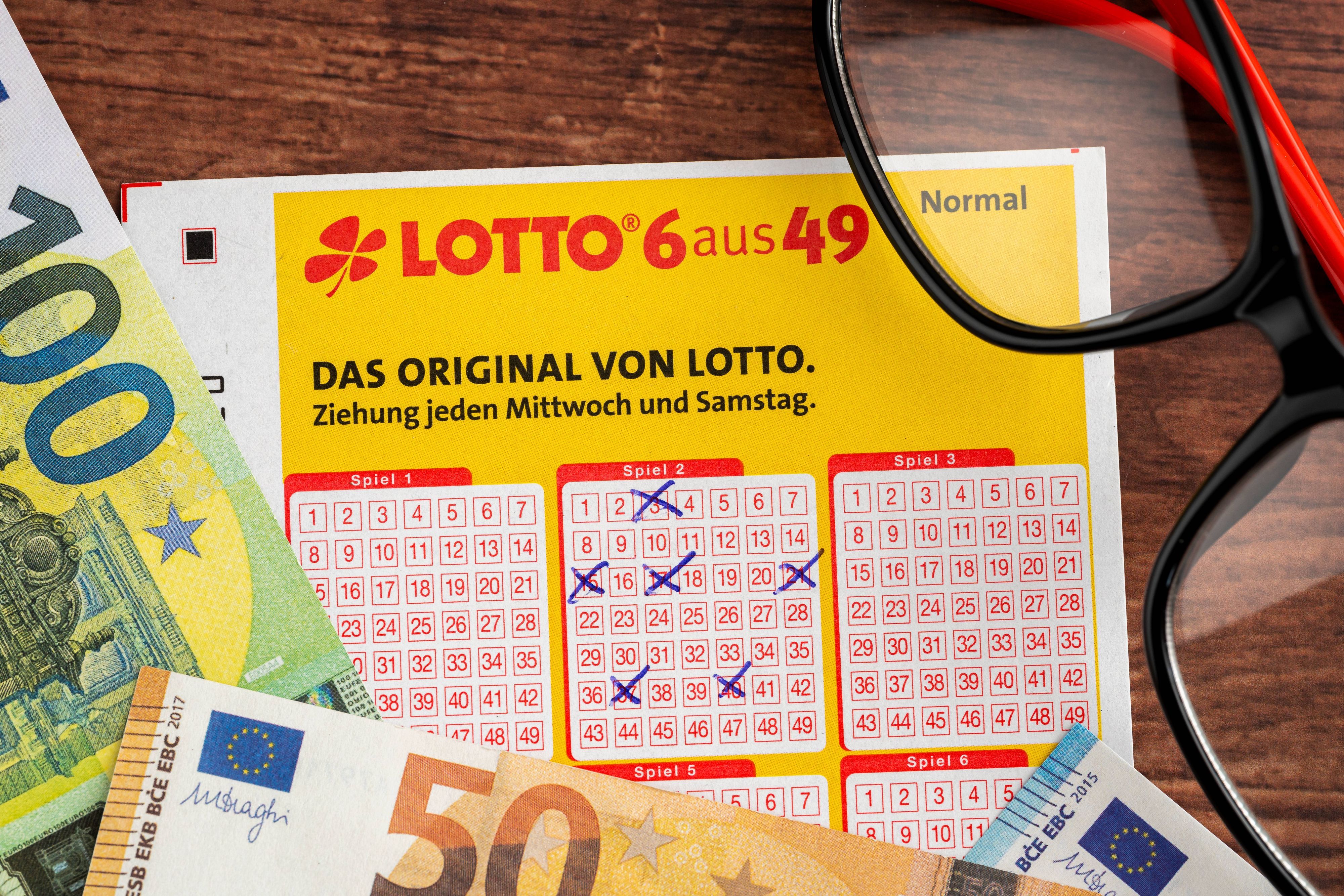Ausgefüllter Lottoschein, Euro-Banknoten und Brille
