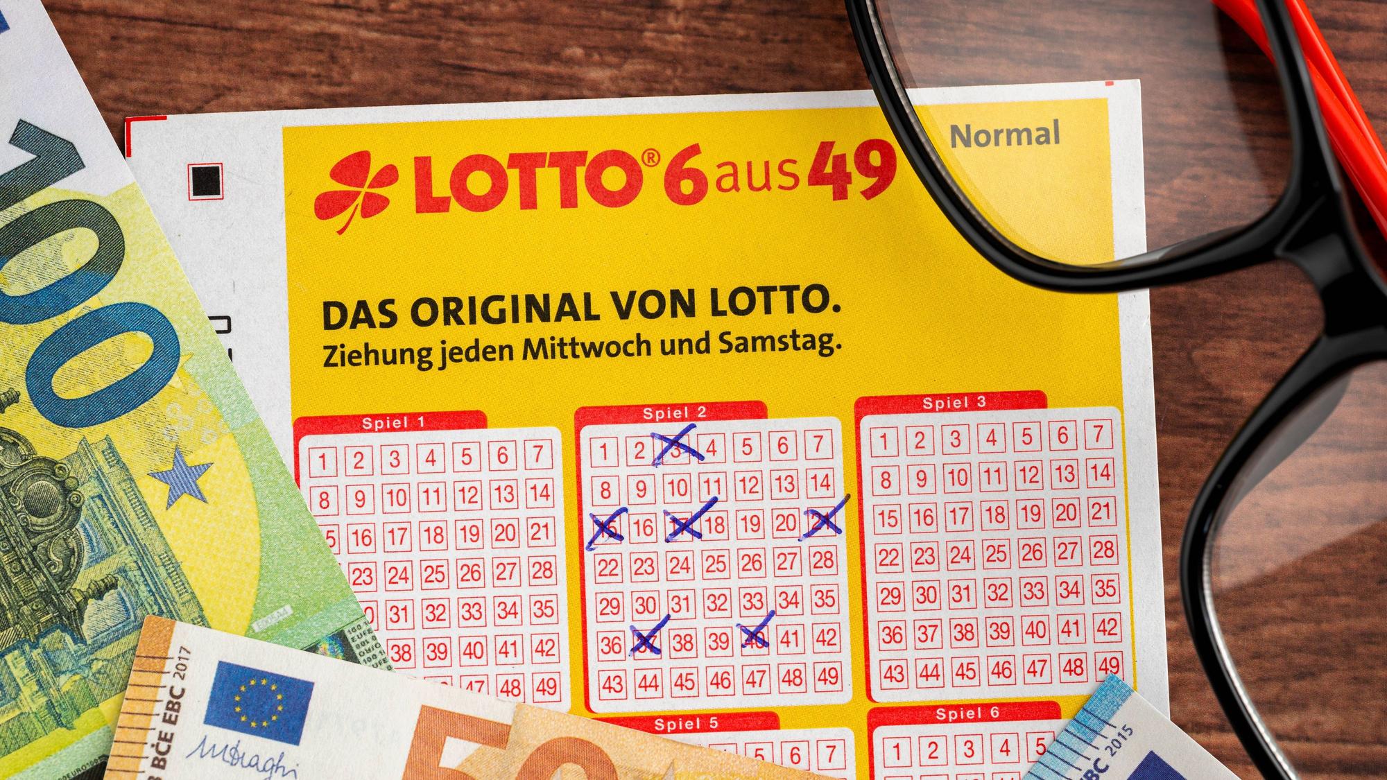 Ausgefüllter Lottoschein, Euro-Banknoten und Brille