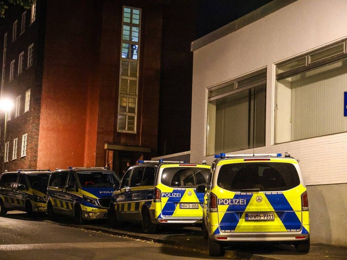 Polizeifahrzeuge stehen bei einem Mehrfamilienhaus.