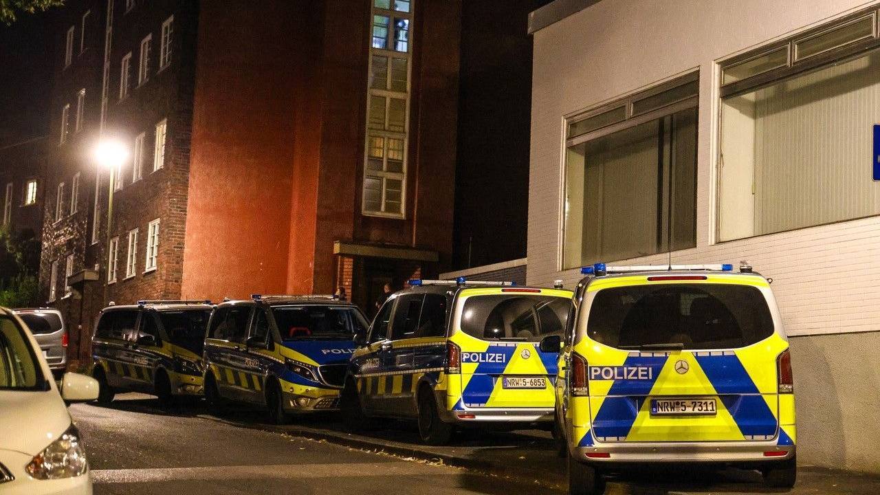 Polizeifahrzeuge stehen bei einem Mehrfamilienhaus.