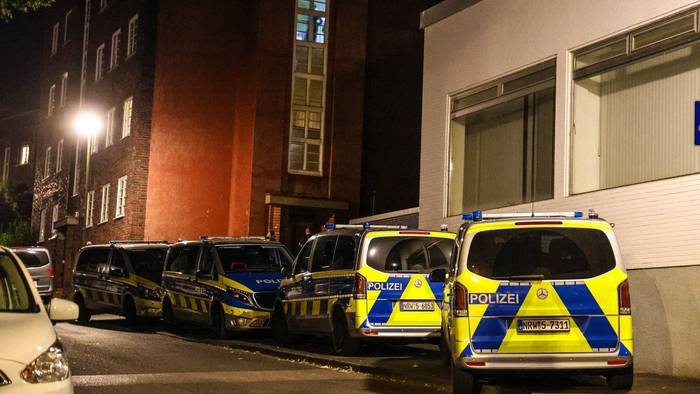 Polizeifahrzeuge stehen bei einem Mehrfamilienhaus.