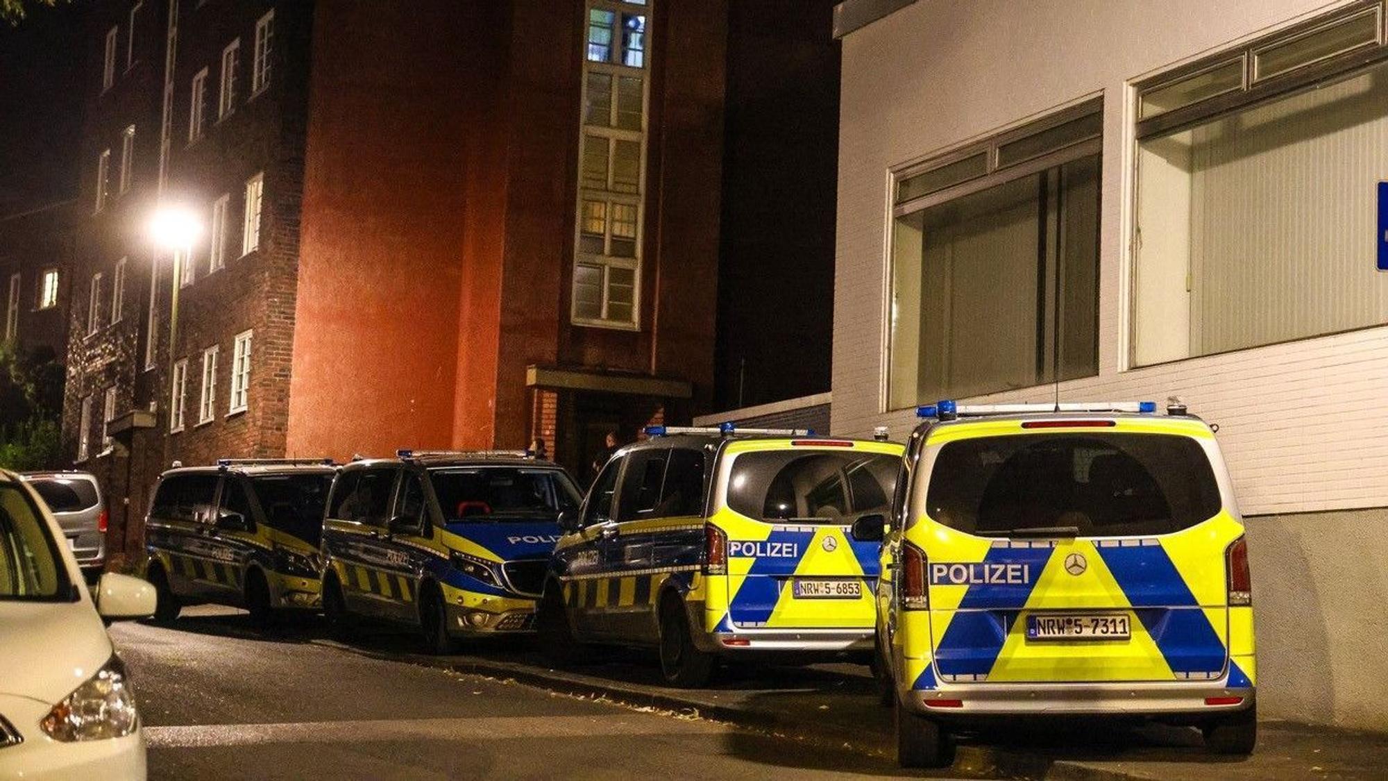 Polizeifahrzeuge stehen bei einem Mehrfamilienhaus.