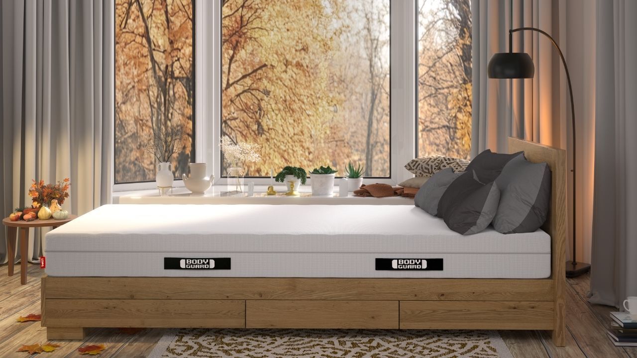 Die BODYGUARD® Anti-Kartell-Matratze® von bett1 vor einem Fenster, draußen herbstliche Stimmung.
